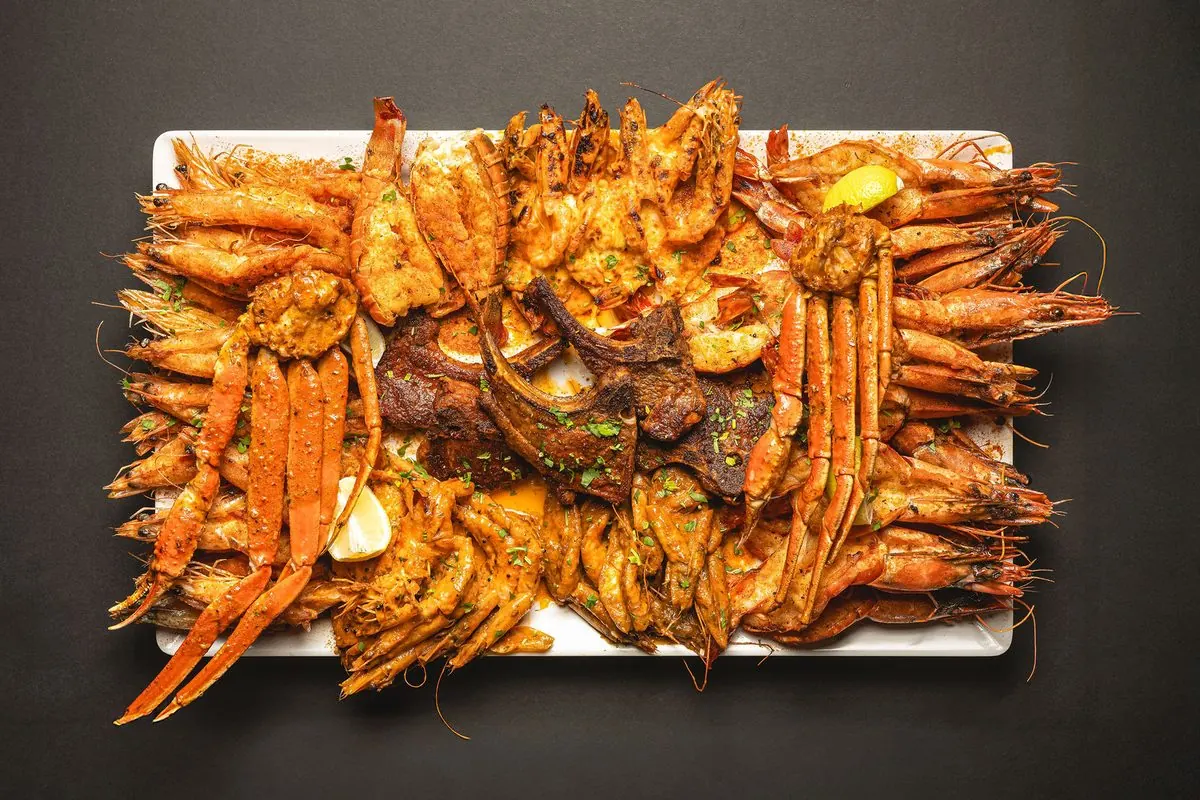A sharing platter piled with snow crab legs, king shrimp and lamb chops