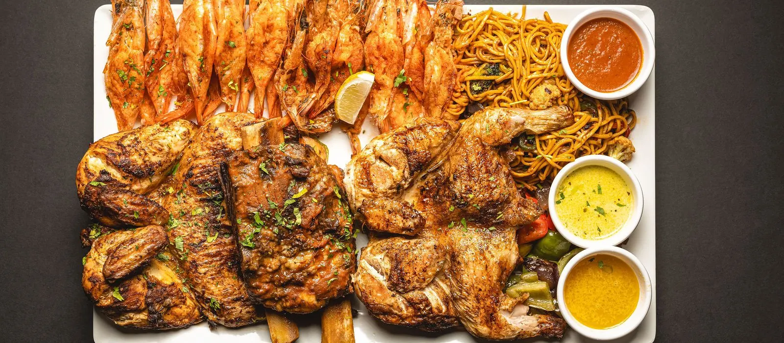 A Shrimp & Co. table spread of grilled chicken, king shrimp, noodles and three dips